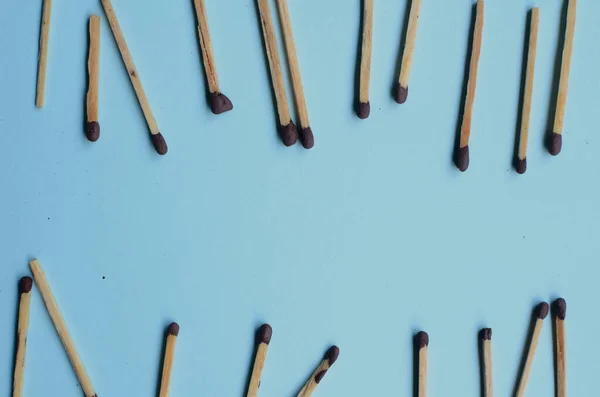 Scattered matches stick on a blue background with copyspace. Top view.