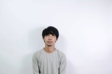 Asyalı adamlar gri uzun kollu tişörtler giyiyorlar. Genç adam boş bir alana baktı.