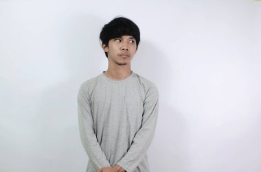 Asyalı adamlar gri uzun kollu tişörtler giyiyorlar. Genç adam boş bir alana baktı.