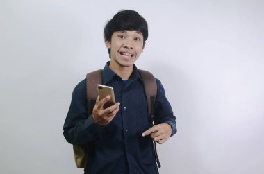 Mavi gömlek giyen ve beyaz arka planda izole edilmiş çantalar taşıyan Asyalı genç adamlar. Cep telefonunun ekranını görünce şok olan genç adamın ifadesi.