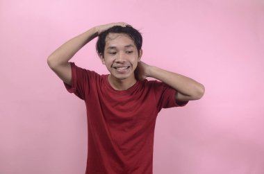 Komik, yakışıklı Asyalı bir adamın mutlu yüzü. Kırmızı tişört giyen Asyalı adamlar pembe arka planda izole edilmiş.