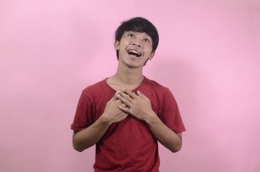 Mutlu Asyalı adamın şaşırmış yüzü. Kırmızı tişört giyen Asyalı adamlar pembe arka planda izole edilmiş.