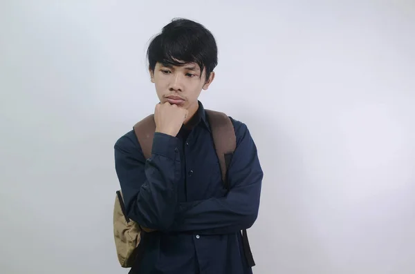 若い男は悲しい表情をしている 青いシャツを着て白い背景に孤立したバッグを持っている若いアジア人男性 — ストック写真
