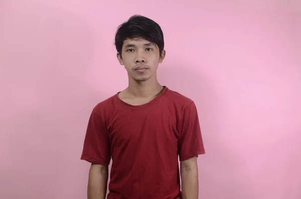 Genç Asyalı ayağa kalktı. Kırmızı tişört giyen Asyalı adamlar pembe arka planda izole edilmiş.