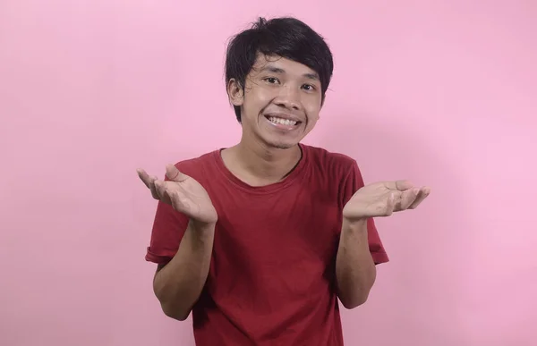 Mutlu Asyalı adamın şaşırmış yüzü. Kırmızı tişört giyen Asyalı adamlar pembe arka planda izole edilmiş.