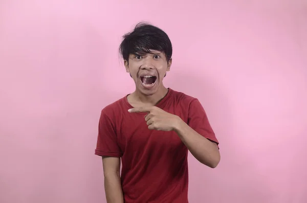 Asian man's shocked face with empty space. Asian men wearing red t shirts isolated on a pink background