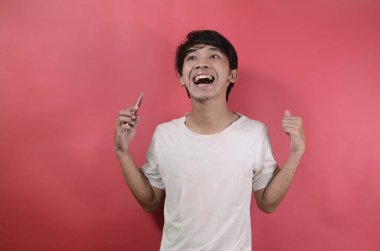 Genç adam mutlu görünüyor. Kırmızı arka planda beyaz tişörtler giyen Asyalı adamlar.