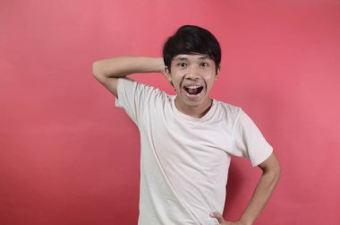 Mutlu bir gencin portresi. Kırmızı arka planda beyaz tişörtler giyen Asyalı adamlar.