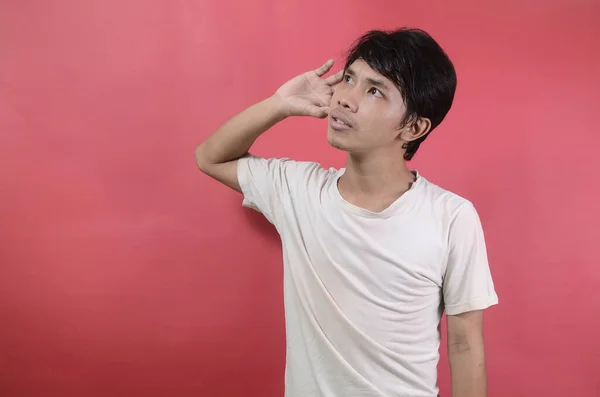 轻松自在的年轻人听对话的形象 亚洲男人穿着红色背景的白色T恤 — 图库照片