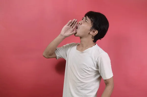 一个年轻人大声叫喊的肖像 亚洲男人穿着红色背景的白色T恤 — 图库照片