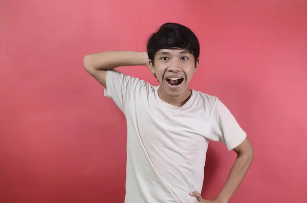 Mutlu bir gencin portresi. Kırmızı arka planda beyaz tişörtler giyen Asyalı adamlar.