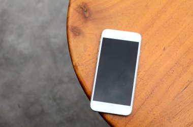 Ahşap bir masada beyaz bir cep telefonu.
