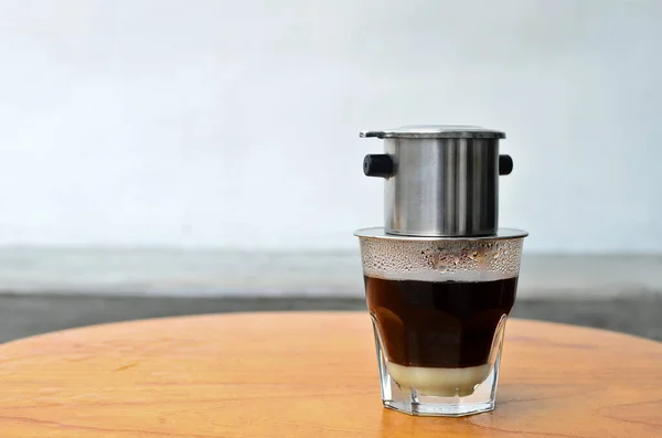 Vietnam usulü sıcak sütlü kahve damlıyor. Tahta bir masada sıcak süt kahvesi.