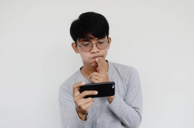 Akıllı telefona bakan kafası karışmış Asyalı bir adamın portresi.