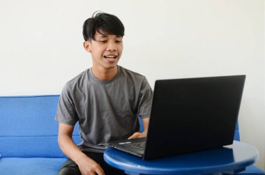 Kanepede oturan Asyalı bir adam.