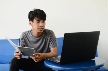 Asyalı adam kanepede oturmuş işiyle meşguldü.