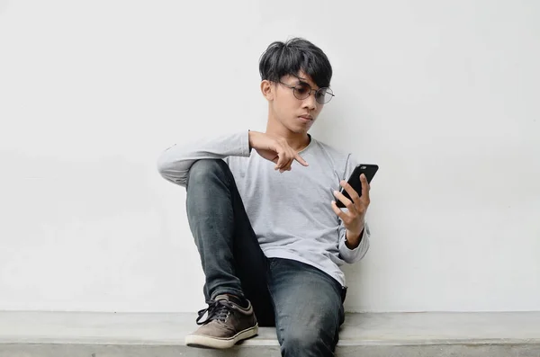 Asiático Jovem Vestindo Óculos Está Sentado Carregando Celular — Fotografia de Stock