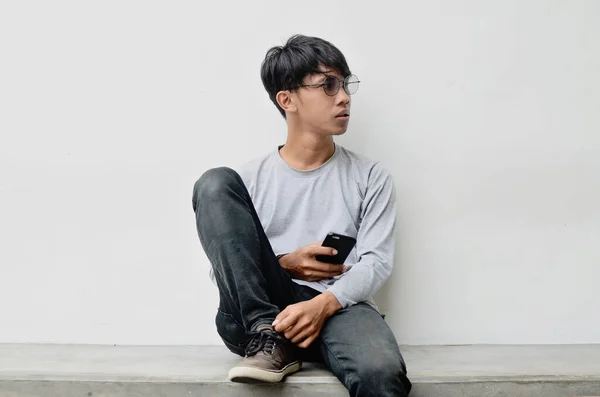 Asiático Joven Usando Gafas Sentado Llevar Teléfono Celular —  Fotos de Stock