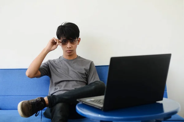 Dizüstü Bilgisayarın Önünde Küllü Tişört Giyen Genç Asyalı Adam Kanepede — Stok fotoğraf