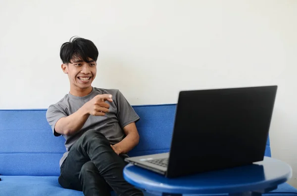 Kanepede oturan Asyalı adam bilgisayarı işaret etti.