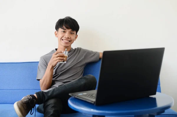 Asyalı gençler kahve içerken dizüstü bilgisayarın önünde oturuyor.