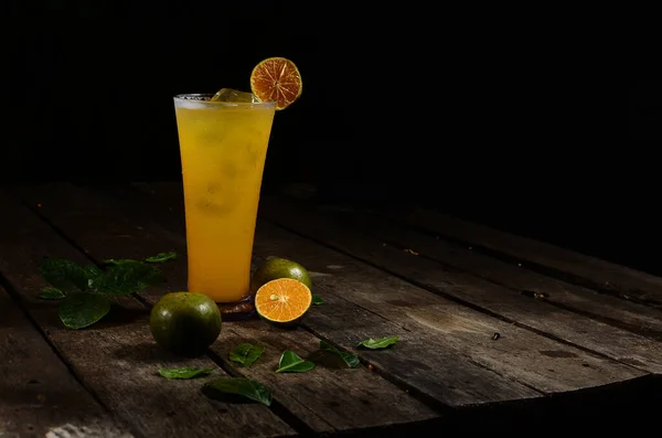 Bir bardak taze sıkılmış portakal suyu ve ahşap bir masada buz küpleri. boş boşluk