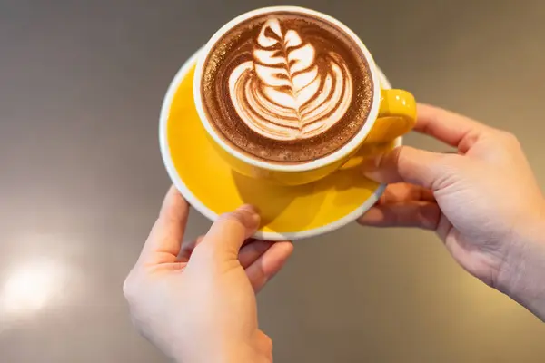İki el üstünde bir fincan çikolatalı latte.