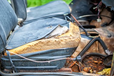 Close-up of torn old seats in a rusty, abandoned, car that stands in the courtyard among the green grass in the open air. The car is disassembled for spare parts. the frame of the car clipart
