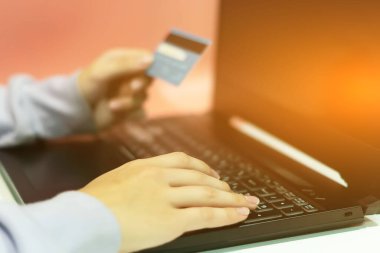 Kız bir dizüstü bilgisayardaki kredi kartıyla internetten alışveriş yapıyor. Çevrimiçi alışveriş