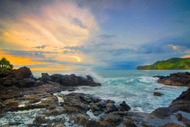 Menganti sahilinde güzel bir gün batımı, Kebumen-Endonezya şehri, kıyılar boyunca sağlam mercan taşlarıyla süslenmiş.