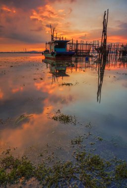Güzel gün batımı ve balıkçı köyü Batam Adası 'nda geleneksel tekne.