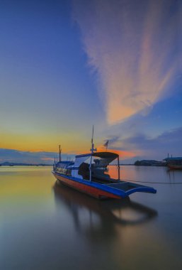 Güzel gün batımı ve balıkçı köyü Batam Adası 'nda geleneksel tekne.