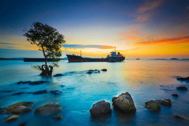 Günbatımında Tanker Gemisi Batam Adası 'nda, kayalarda yosun
