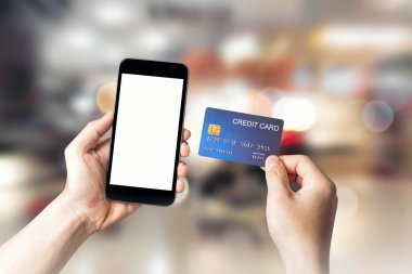 Akıllı cep telefonlu eller alışveriş merkezinin arka planında, elektronik ödeme teknolojisinde, internet bankacılığı kavramında tasarımınız için beyaz ekran arkaplanı gösteriyor.