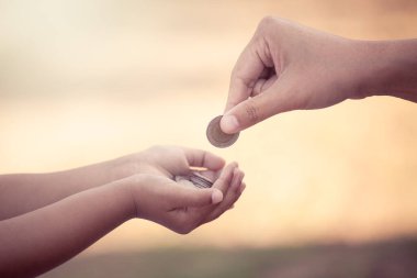 Anne çocuğa para vermek para biriktirmek için klasik renk tonuyla para veriyor.