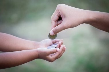 Anne çocuğa para vermek para biriktirmek için klasik renk tonuyla para veriyor.