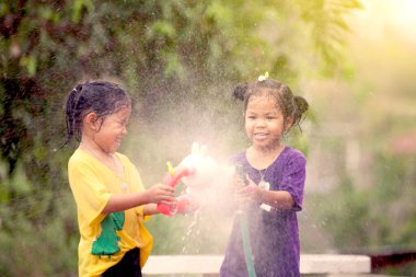 İki Asyalı küçük kız Songkran festivalinde birlikte su oynayarak eğleniyorlar Tayland 'da.