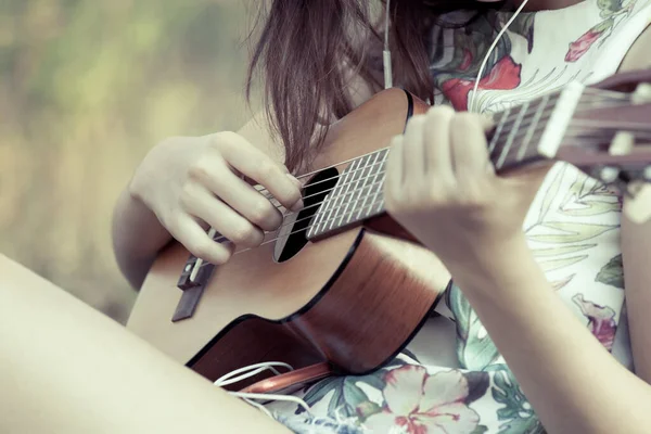 年轻的亚洲女人在公园里弹奏着古色古香的吉他 — 图库照片