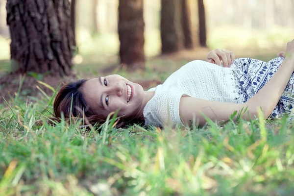 快乐的年轻亚洲女人躺在公园的草地上 用古色古香的色调 — 图库照片