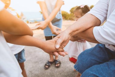 Asyalı aile el ele tutuşup destek veriyor. Aile nesli birlik ve takım çalışmasını göstermek için el ele tutuşur.