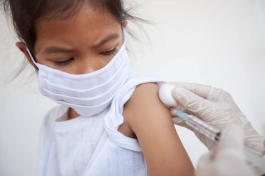 Doktor, Asyalı çocuk koluna aşı yapıyor. Başbakan 2.5 ve Covid-19 virüsleriyle hava kirliliğini korumak için koruyucu maske takan kız çocuğu. Sağlıklı ve tıbbi konsept.