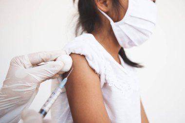 Doktor, Asyalı çocuk koluna aşı yapıyor. Başbakan 2.5 ve Covid-19 virüsleriyle hava kirliliğini korumak için koruyucu maske takan kız çocuğu. Sağlıklı ve tıbbi konsept.