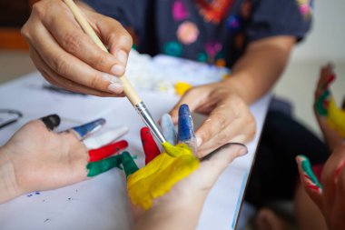 Ebeveynler çocukların ellerini suluboya ve eğlence ile boyuyor. Aile, Coronavirus Covid-19 karantinasında kalırken etkinlik gösteriyor..