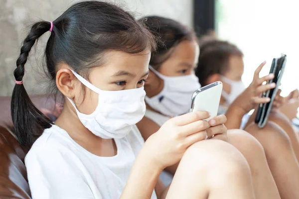 Asiático Crianças Menino Meninas Vestindo Máscara Proteção Jogando Smartphone Juntos — Fotografia de Stock