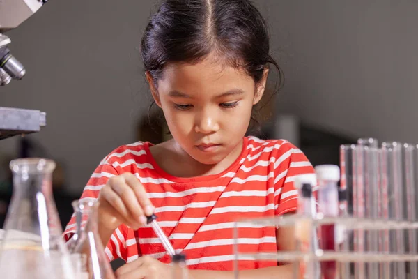 Asian child girl making chemical experiment in the laboratory.