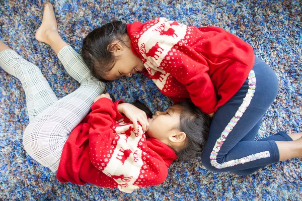 二つのかわいいアジアの子供たちが床の上に横たわって一緒にクリスマスのお祝いで遊ぶ — ストック写真