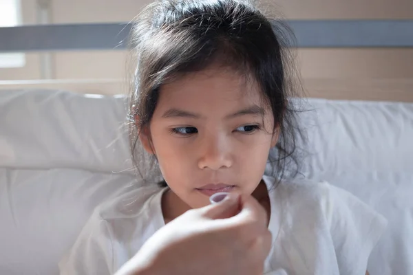 アジアの母親与え咳止めシロップ薬上の彼女の娘にスプーンでベッド 病気の子供と健康管理の概念 — ストック写真