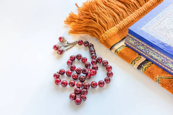 Tasbih or rosary beads, prayer mat and Holy Quran on white background. Selective focus.