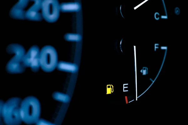 car dashboard shows low fuel warning light, selective focus