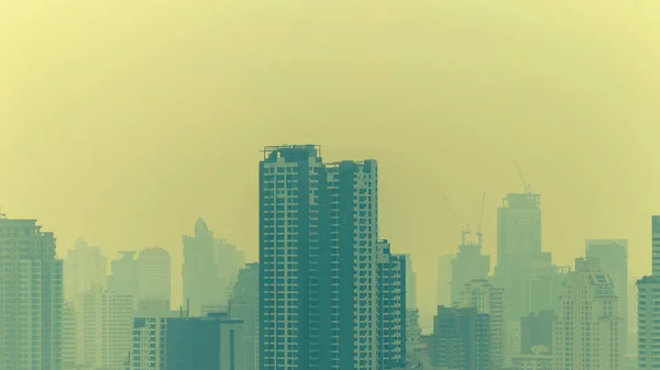 cityscape of high rise buildings in poor weather morning, haze of pollution covers city, global warming concept